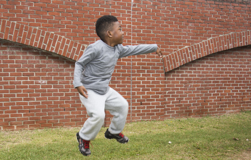 Boy jumping with a brick background